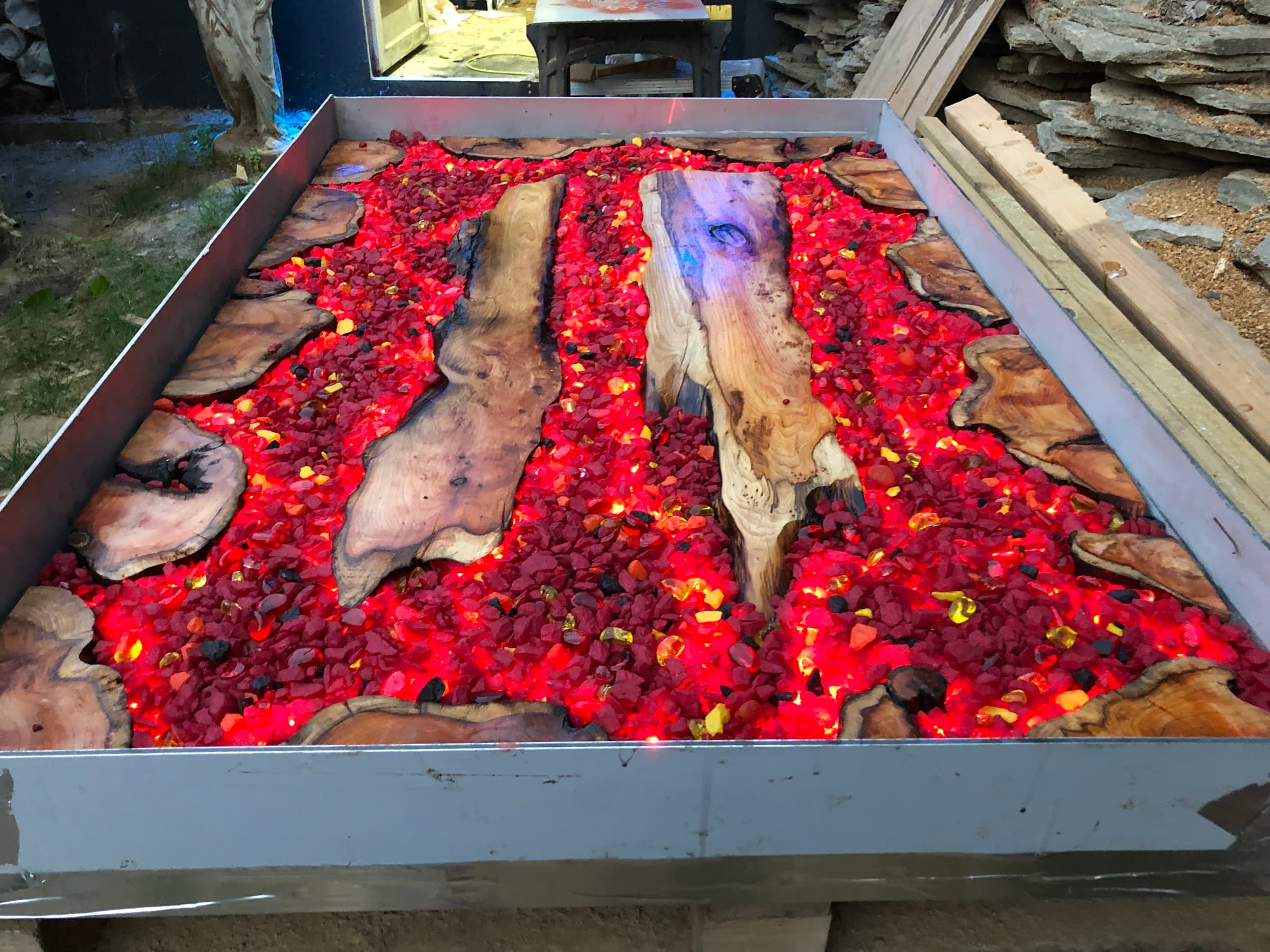 Steel-framed tray table filled with red glass and live-edge timber, LED-lit from within like embers