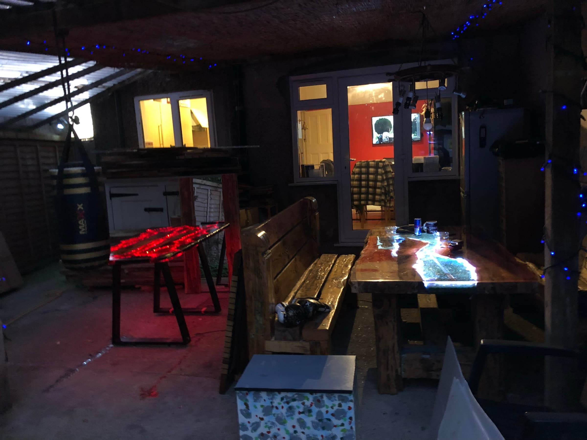 The table and a related piece glowing red and blue in a dim workshop/garden-room setting at night
