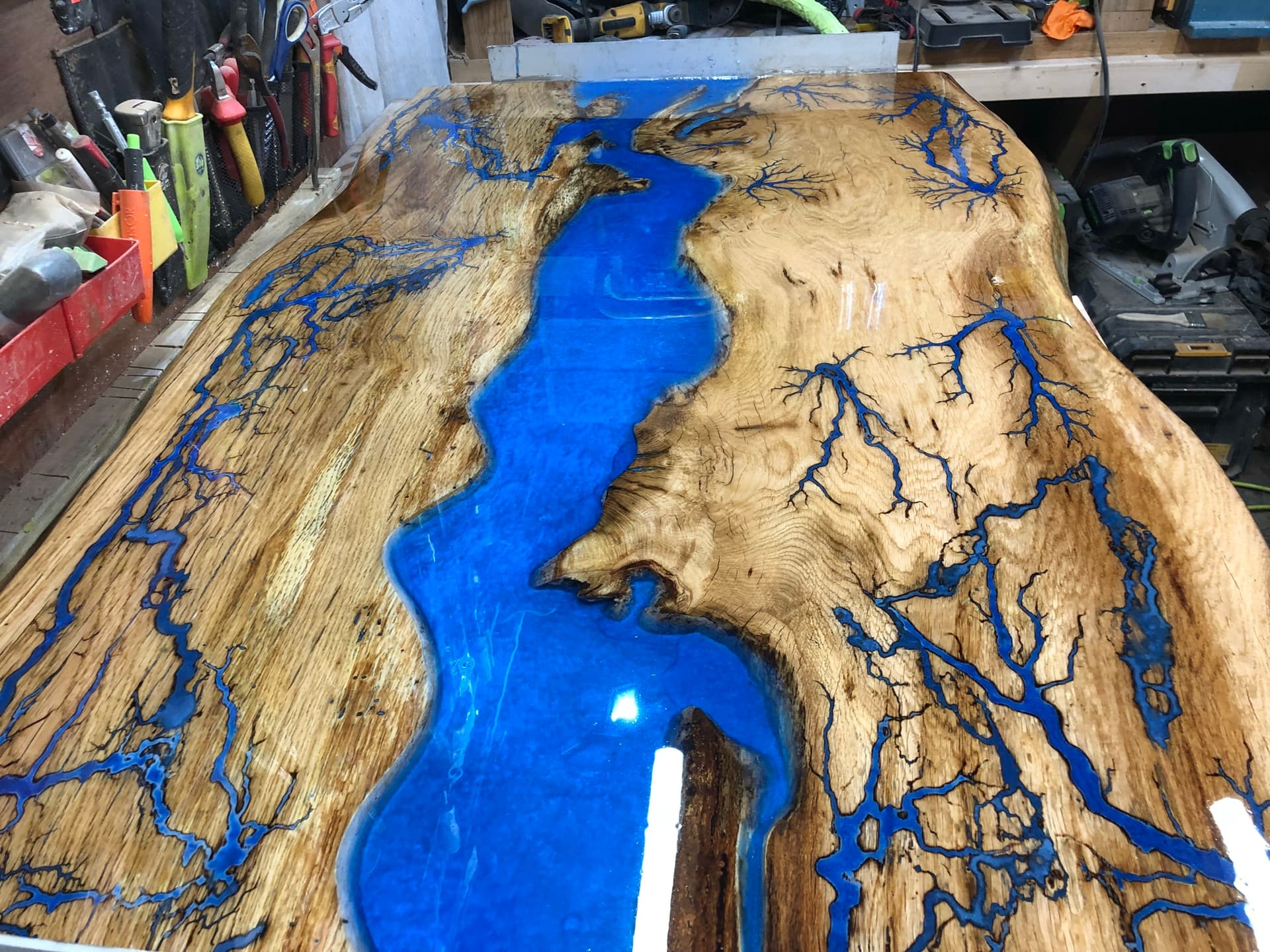 Full tabletop with a wide blue resin river and Lichtenberg branching through natural timber