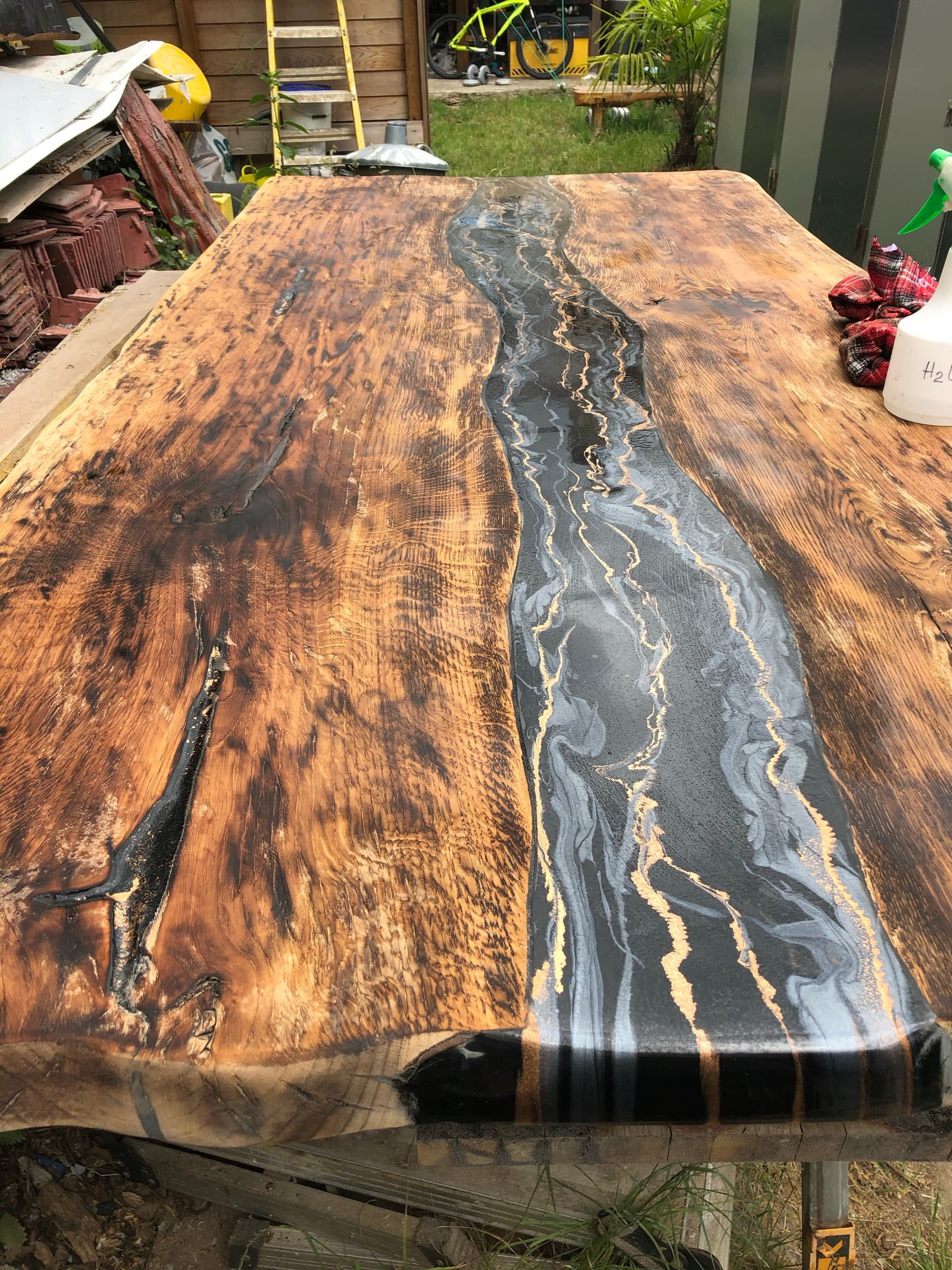 Close top-down view of the black and gold marbled resin river through scorched wood