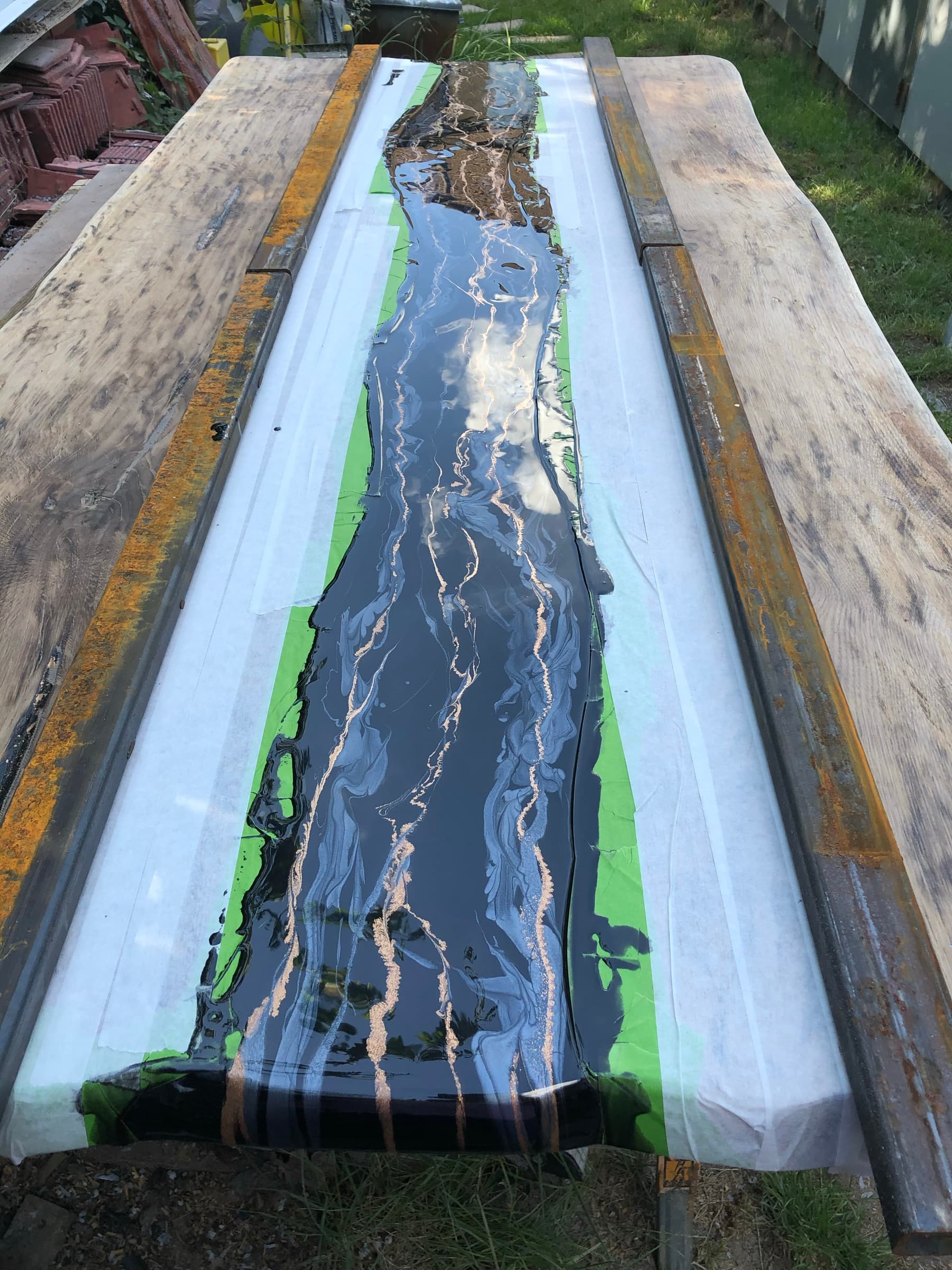 The slab cast in a taped mould, black resin with gold veining still curing