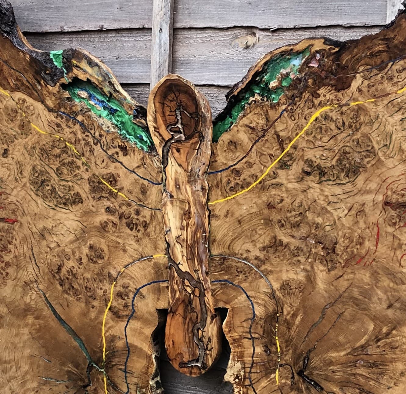 Close crop of the carved body and wing-root detail, showing painted Lichtenberg veining and green resin voids