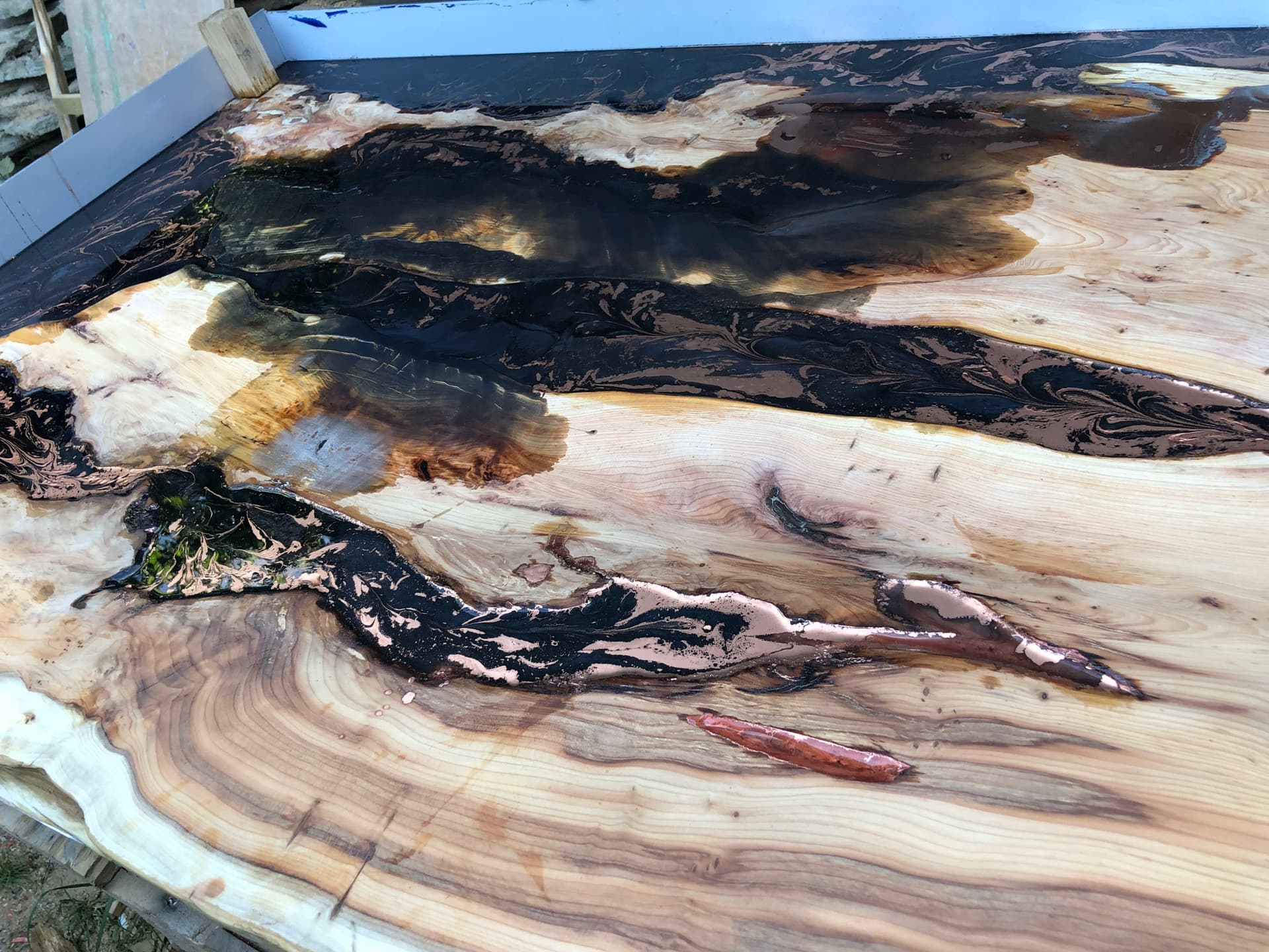 Close detail of the black resin river swirled with metallic copper through yew grain