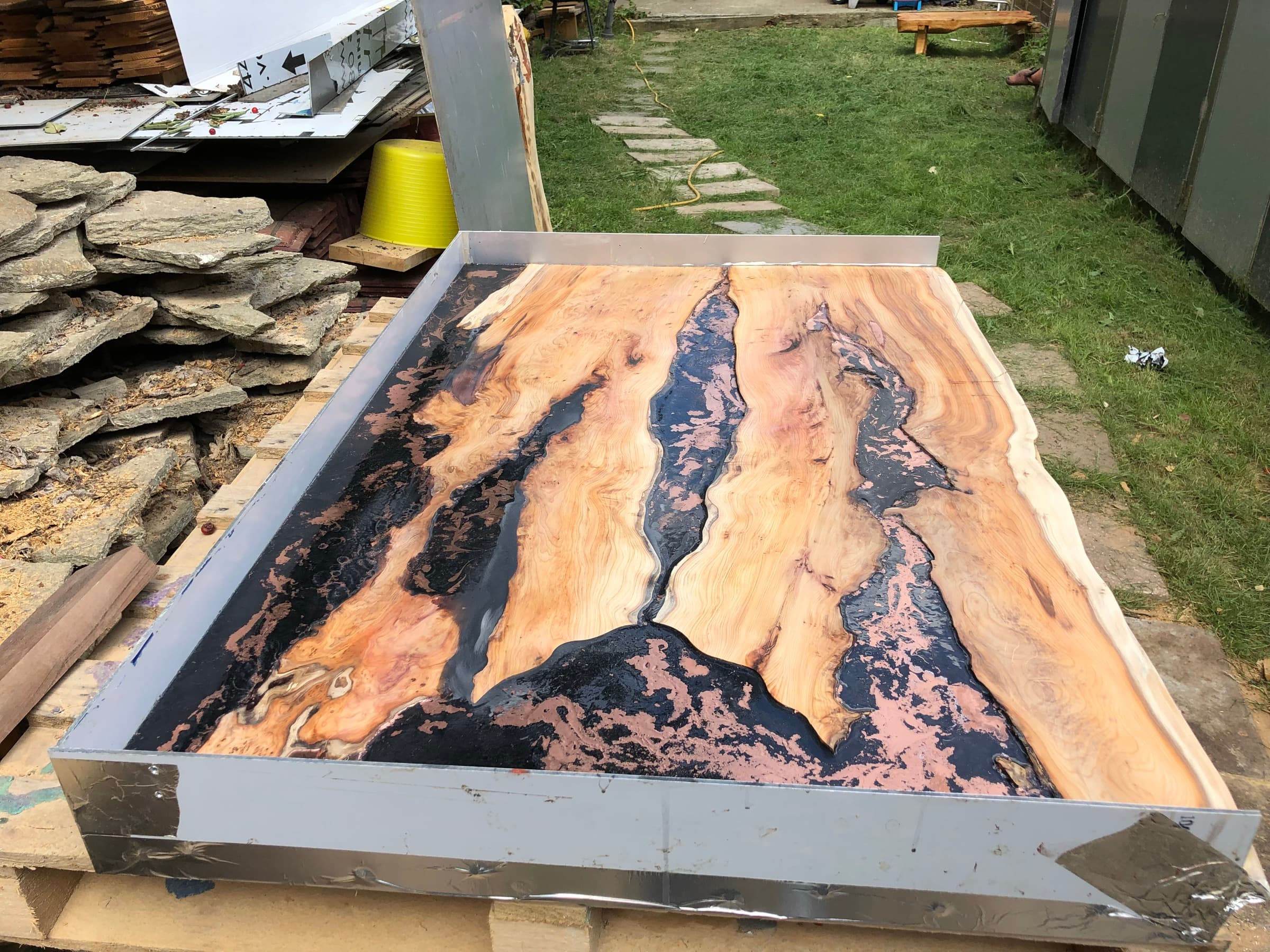 The tabletop still in its steel casting mould, black and copper river pattern visible before release