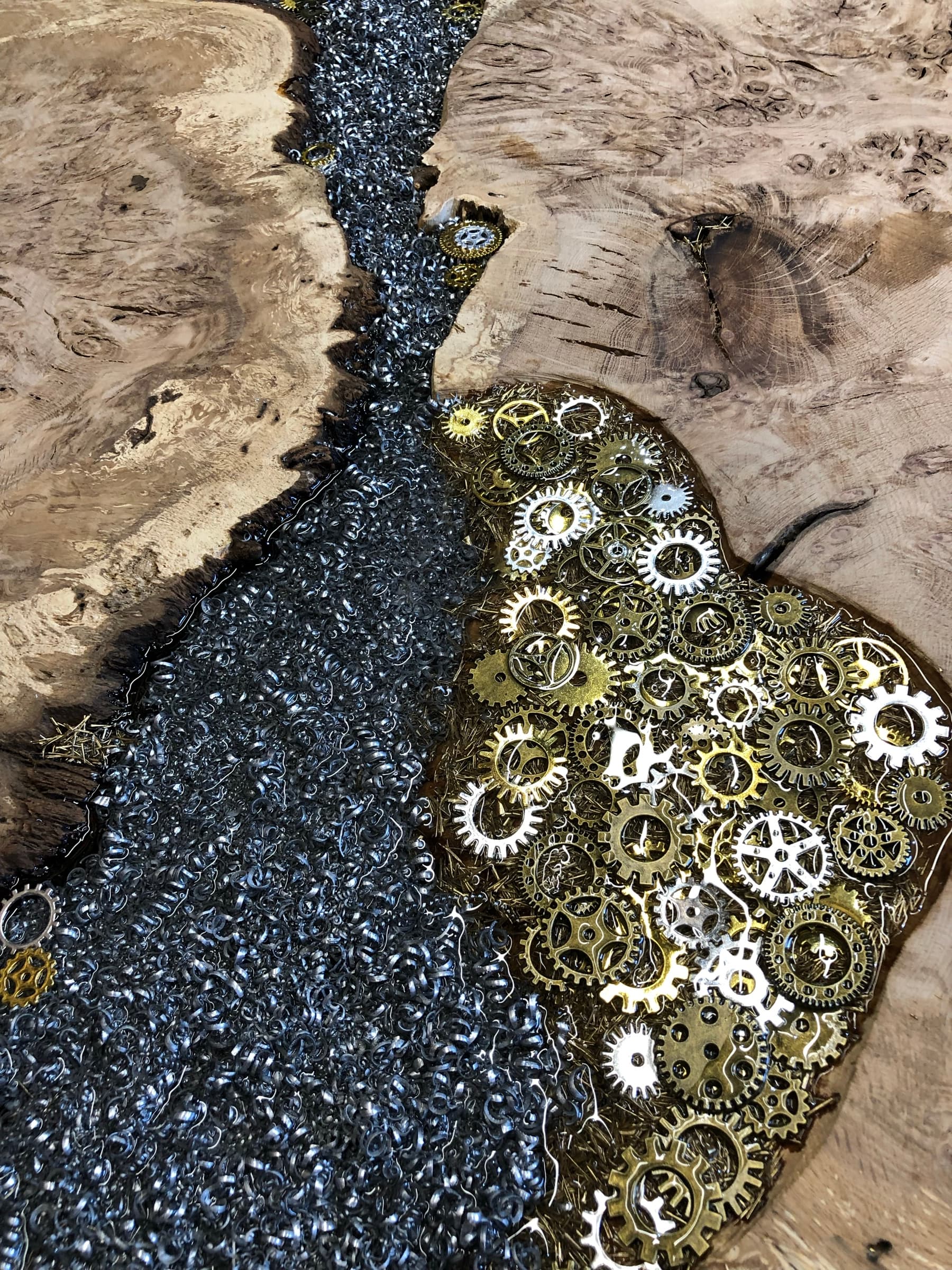 Macro detail of steel shavings flowing into a cluster of brass and steel watch gears, set in resin