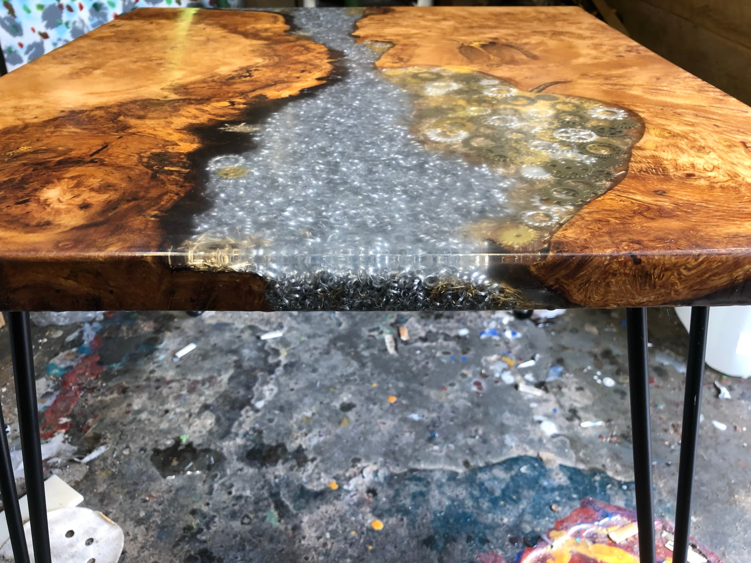 Burl side table with a river of steel shavings and gears through the centre, on black hairpin legs