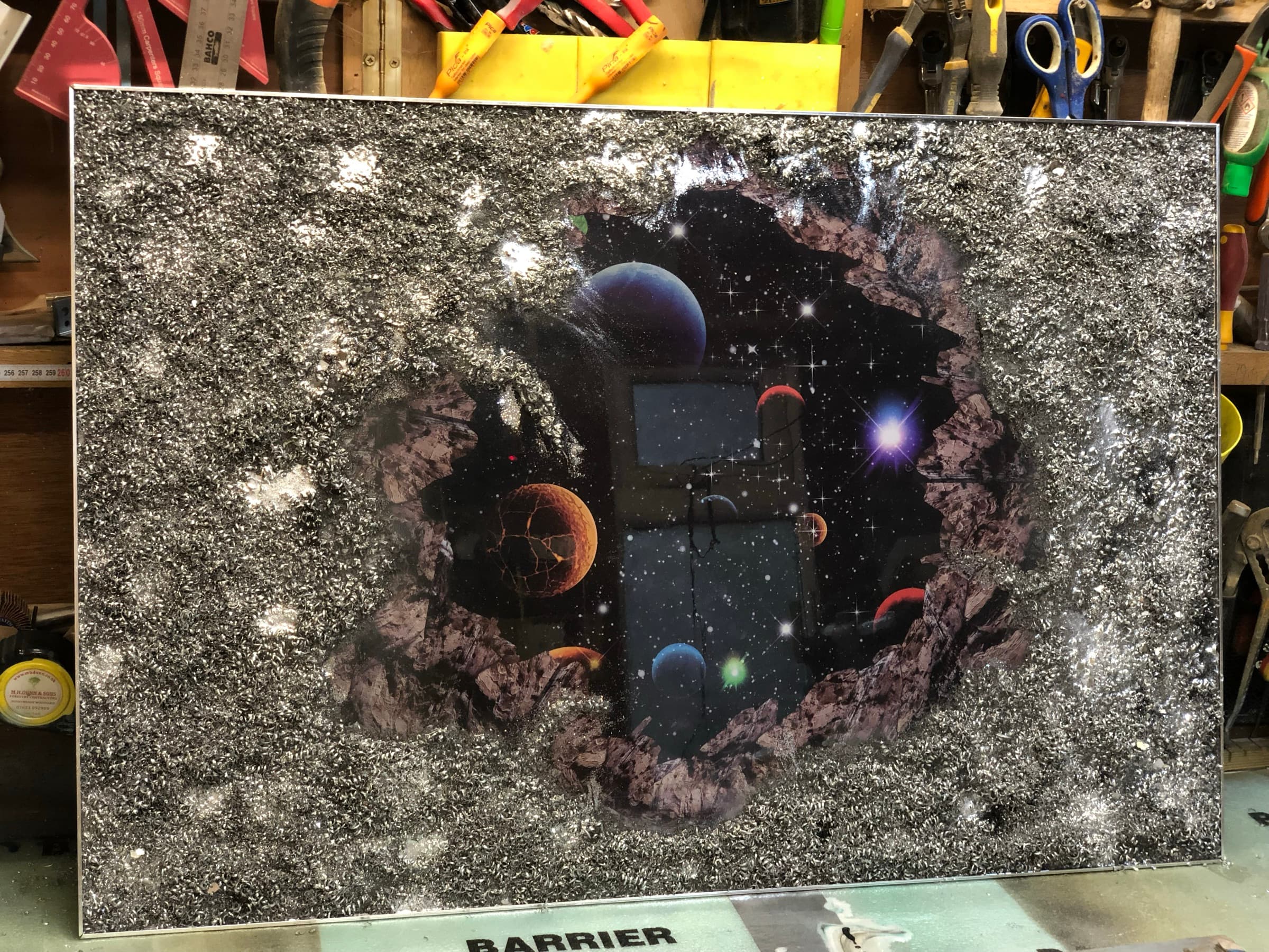 The full wall panel, textured surround broken open around a painted space scene, workshop