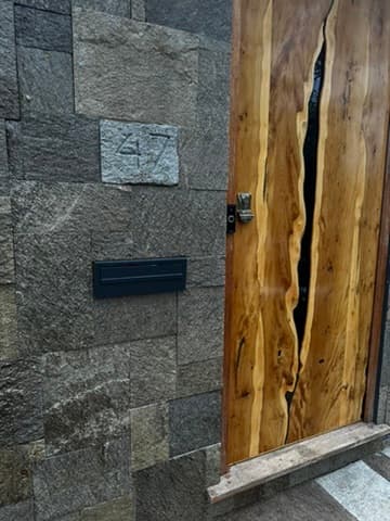 Daylight view of the door edge, house number 47 and letterbox set into the stone