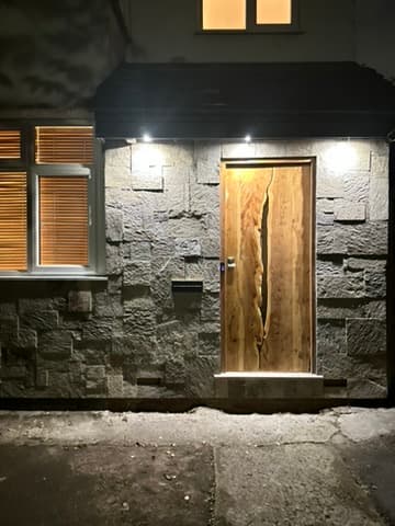 The fitted front door at night, stone-clad house entrance, warm uplighting either side