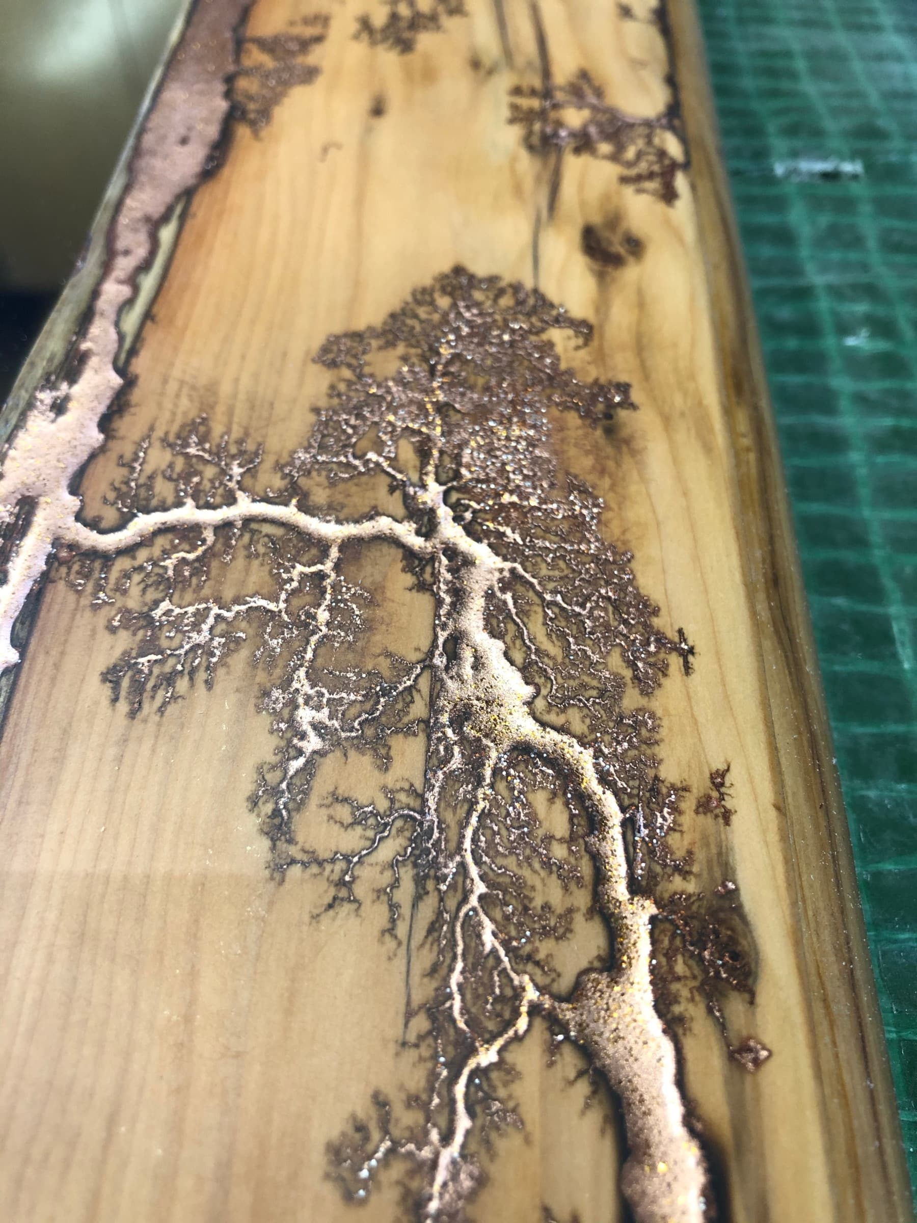 Close detail of the Lichtenberg branching burned into the frame and filled with copper, on the workbench