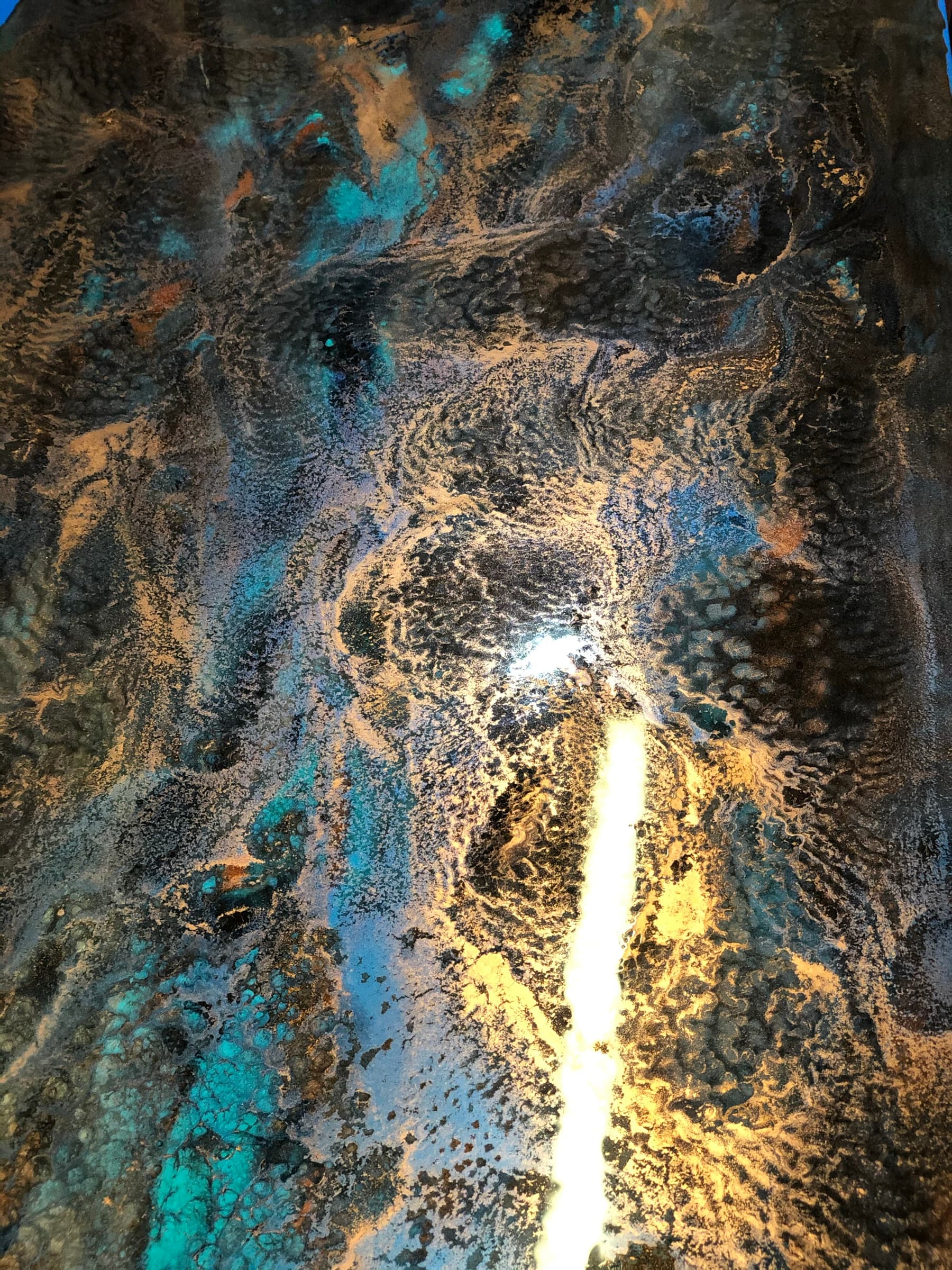 Close detail of the blue and copper marbled patina on the mirror surface