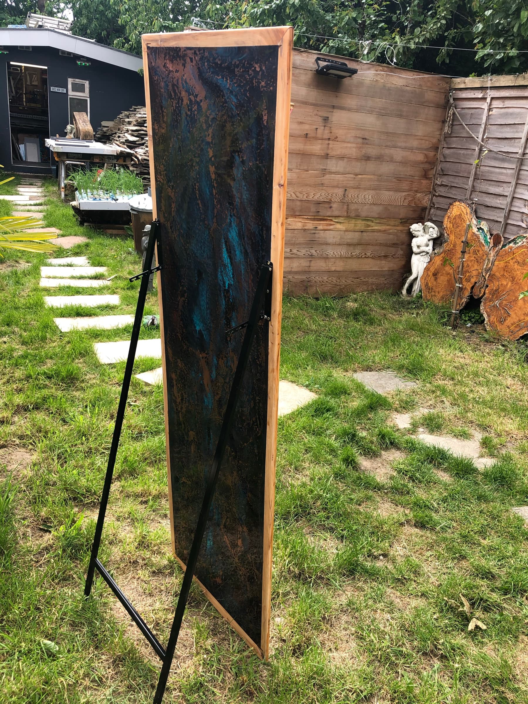 The full free-standing mirror on an easel stand outdoors, light timber frame and patinated surface