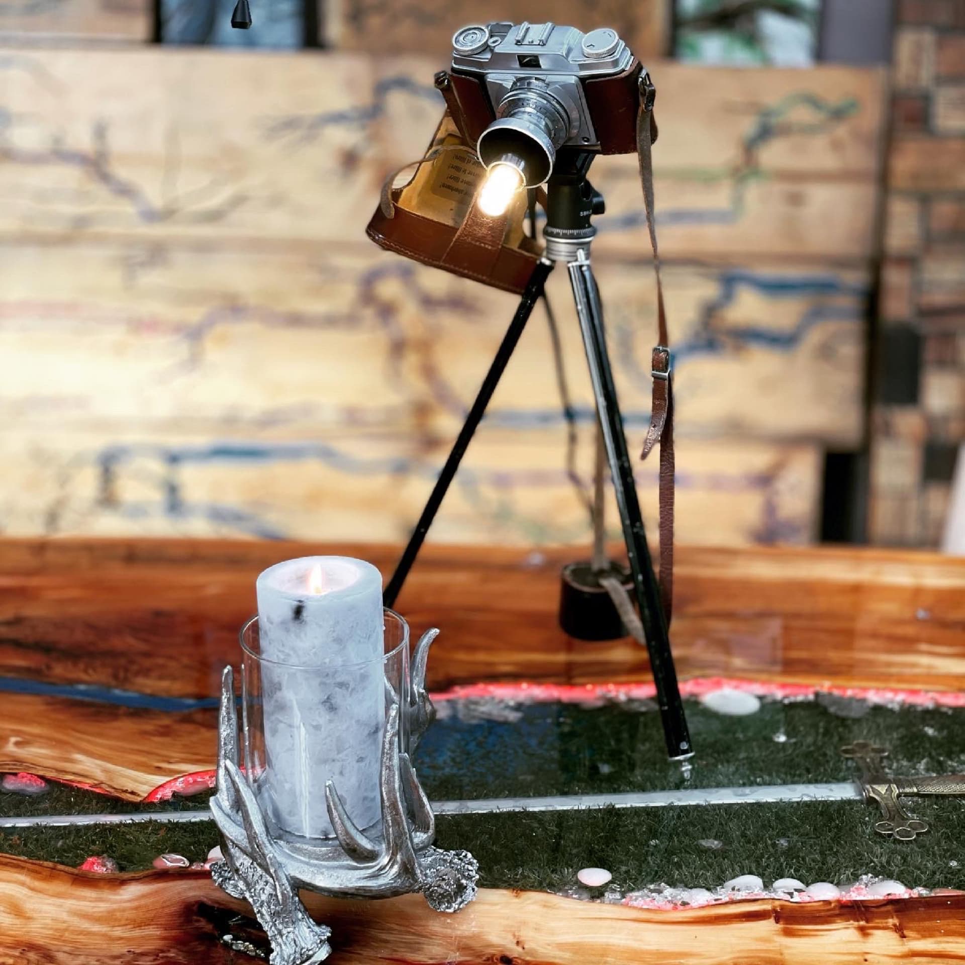 The camera lamp's bulb pointed at a lit candle in an antler-shaped holder, both light sources in one frame, on the Prince and the Beggar table