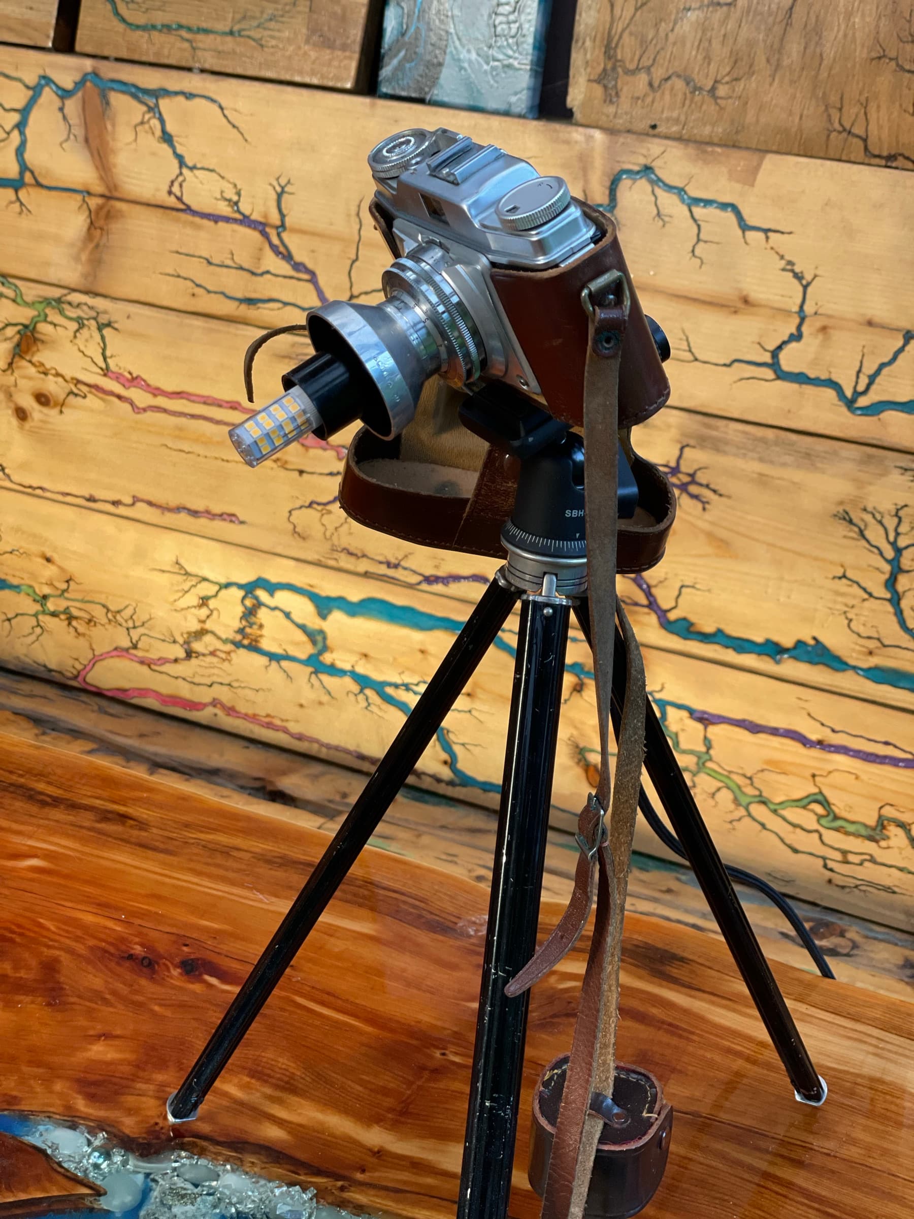 The camera lamp on its tripod, lit, standing on the Prince and the Beggar tabletop