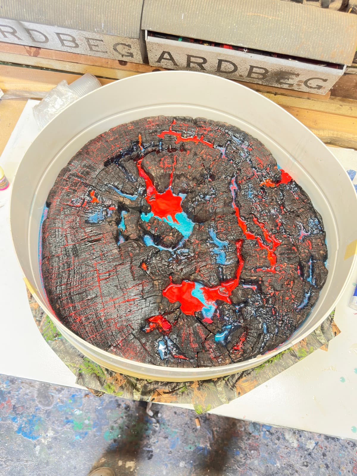 A round timber disc, deeply charred, sitting in a circular mould before resin is poured