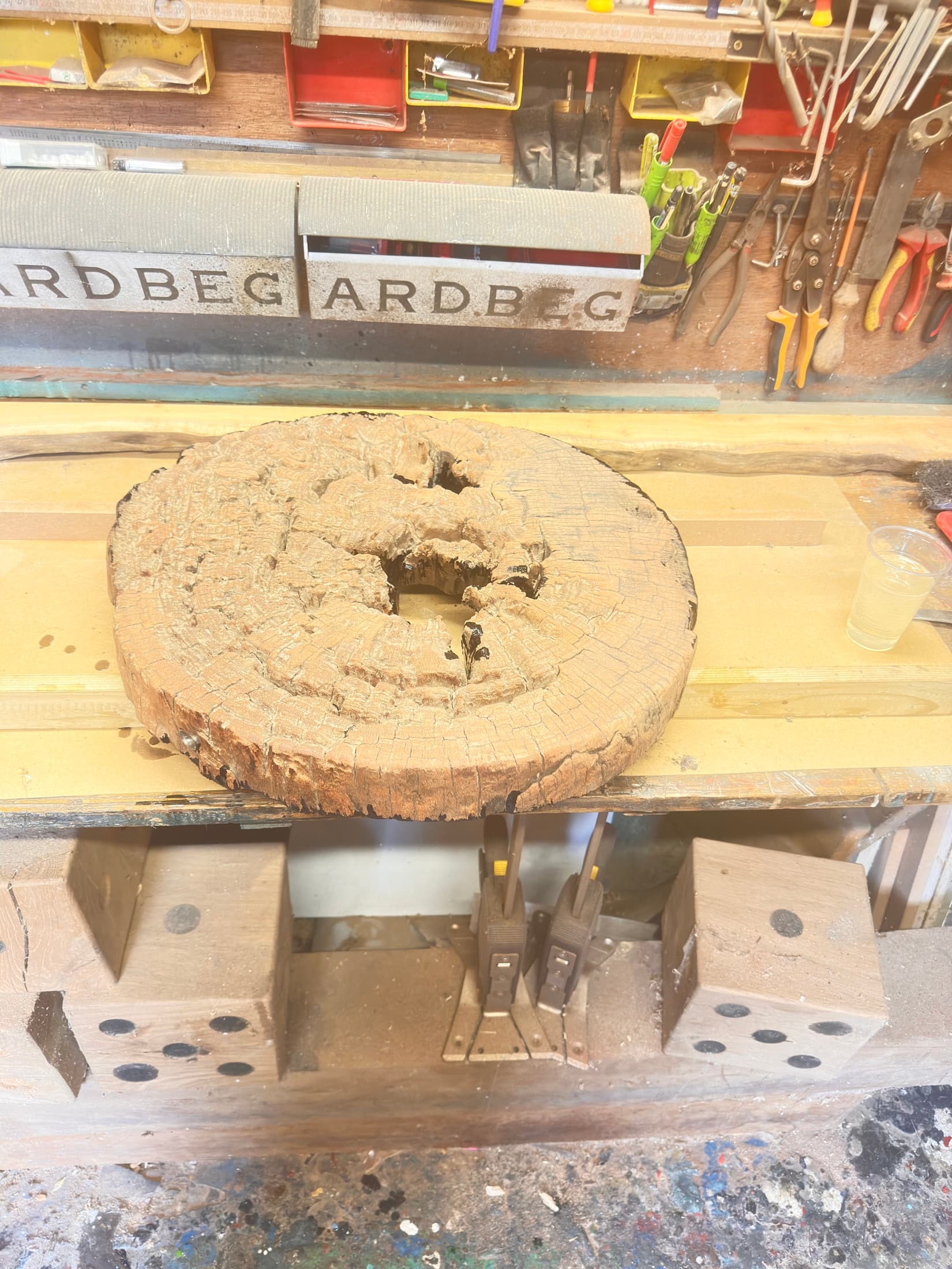 A raw, unburned timber disc on a workshop bench, before treatment