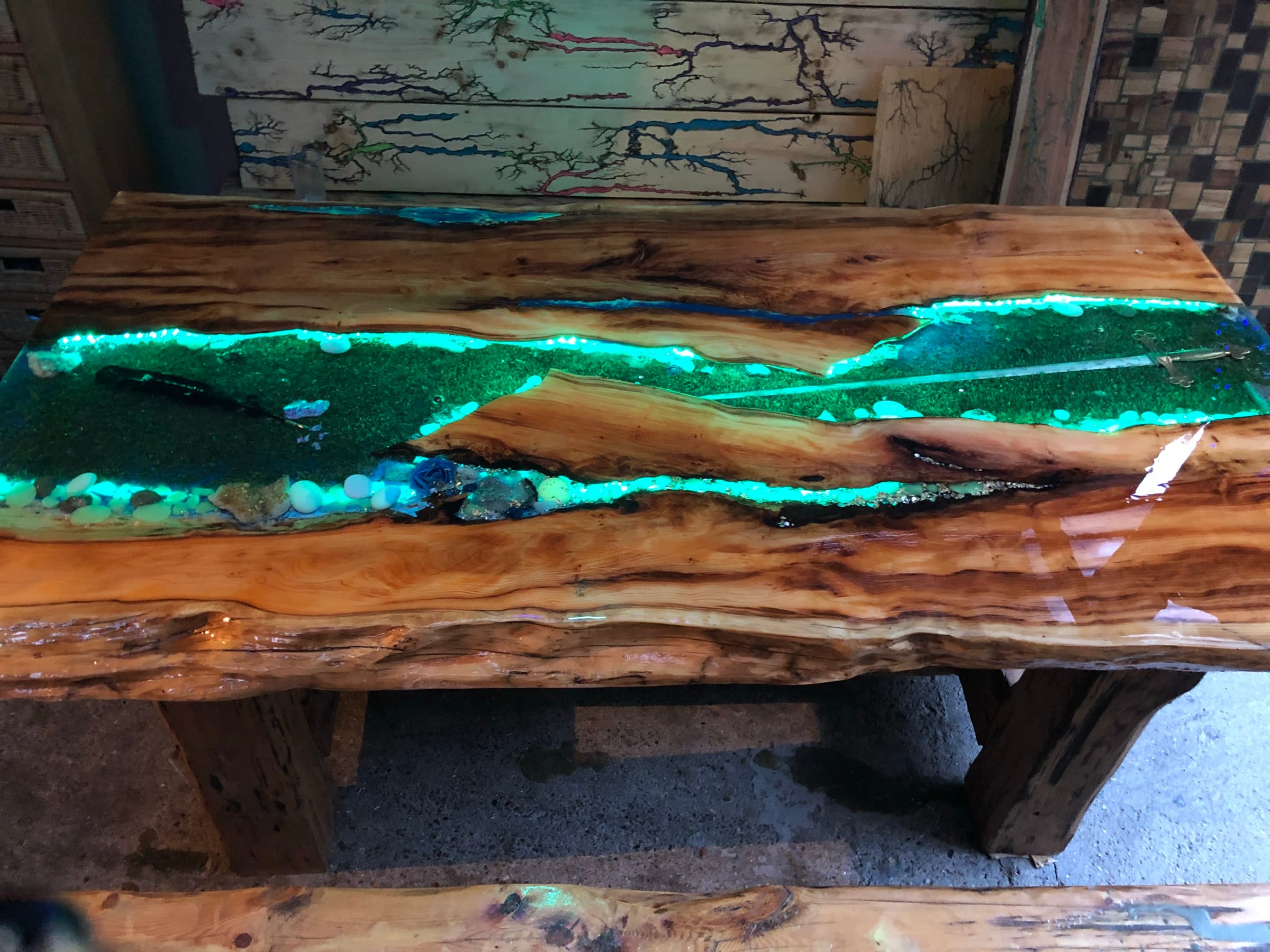 The table in the workshop, glowing green under UV, alongside other pieces in progress