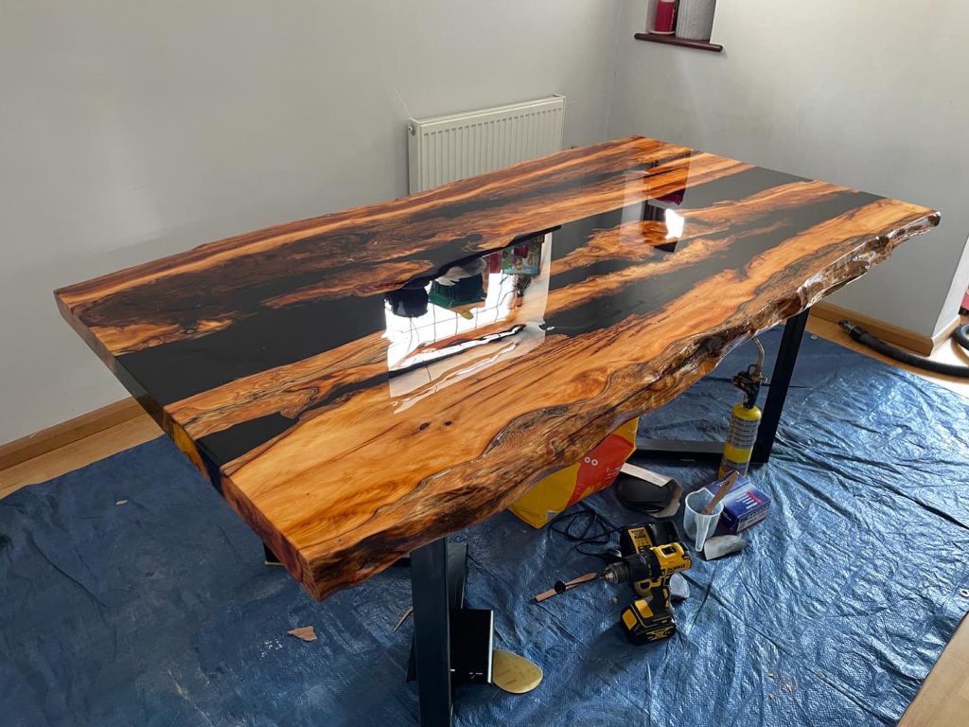The finished table from a second angle, overhead light reflecting in the black resin