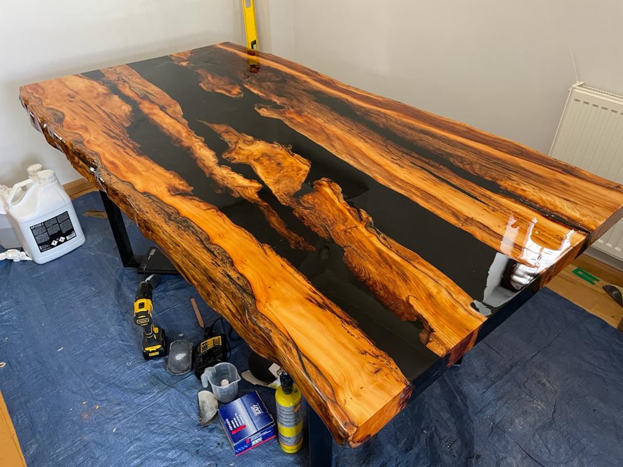 The finished Tiger Yew table indoors on protective sheeting, black resin channels through striped yew grain