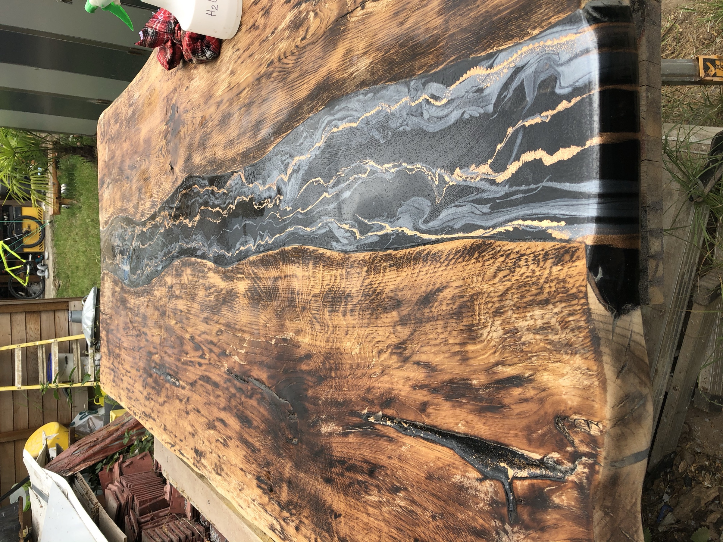 Close top-down view of the black and gold marbled resin river through scorched wood