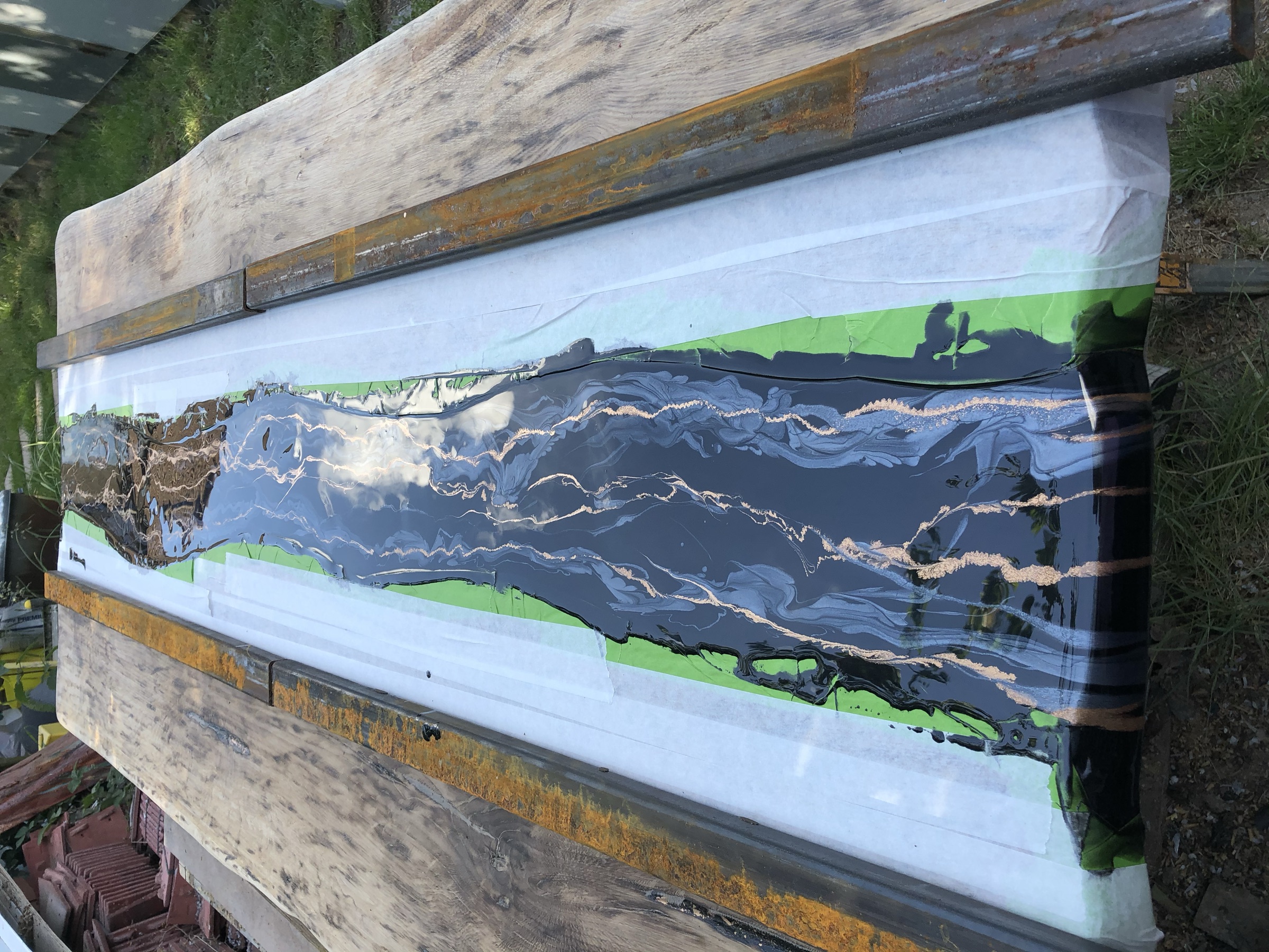 The slab cast in a taped mould, black resin with gold veining still curing