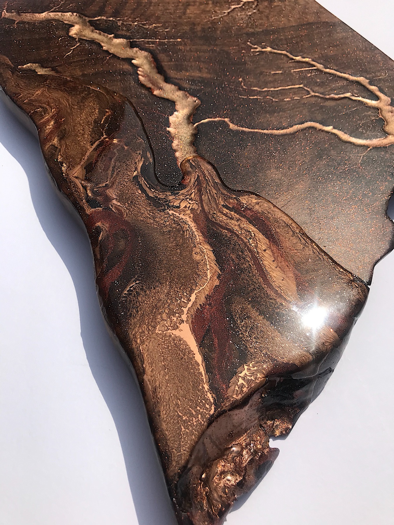 Close macro of gold Lichtenberg branching across a live-edge board, glitter-flecked resin