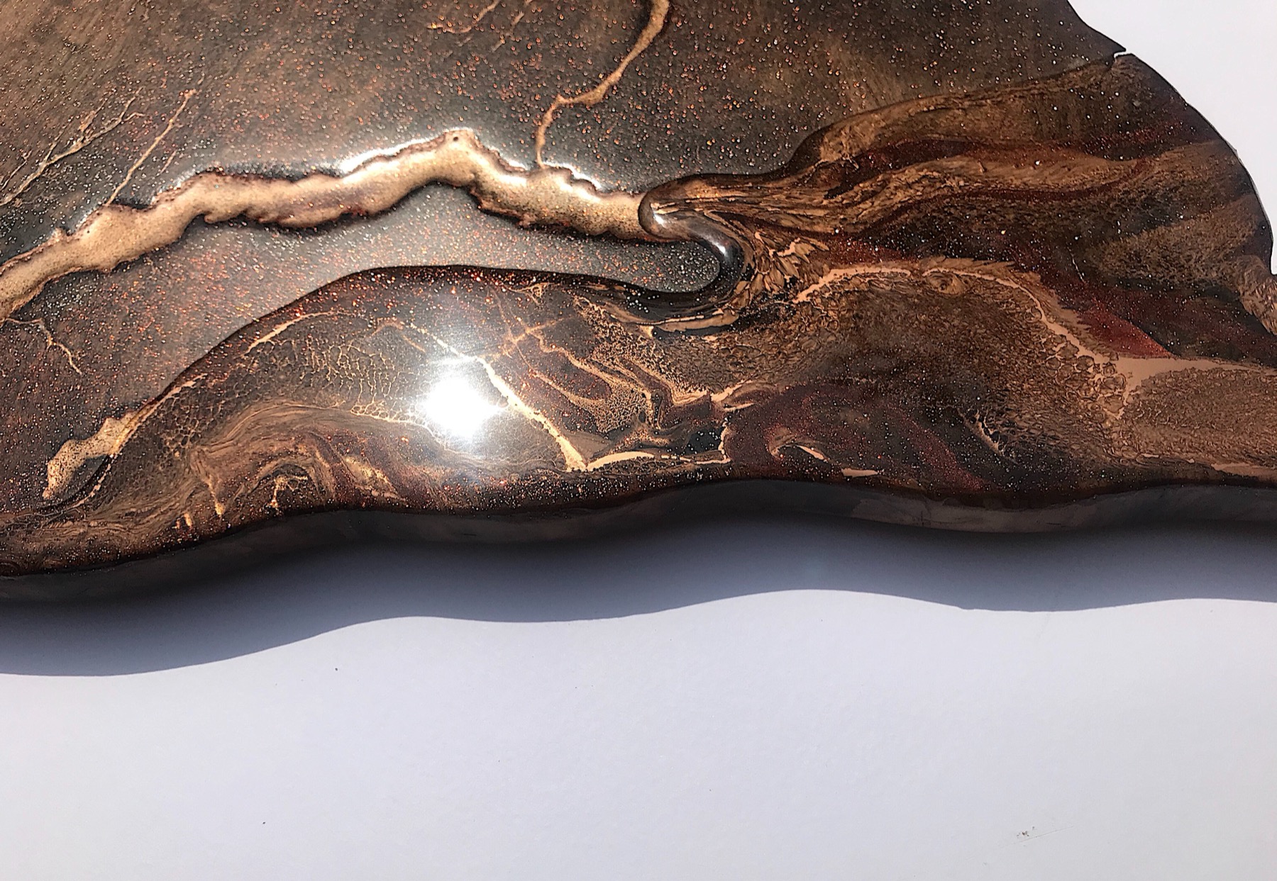 Warm-toned macro of Lichtenberg branching filled with metallic pigment