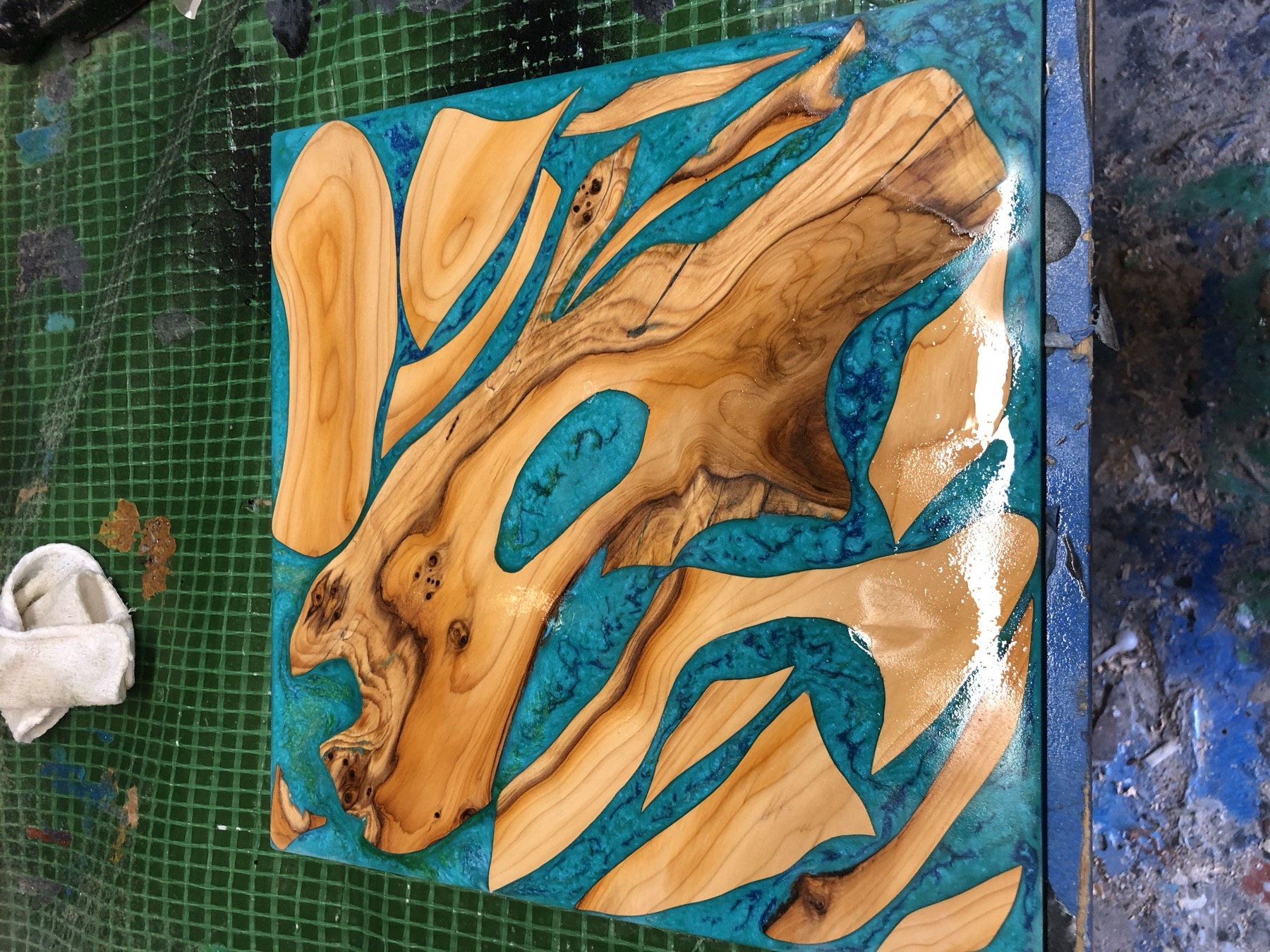 Macro of turquoise and gold glitter resin through olive burl