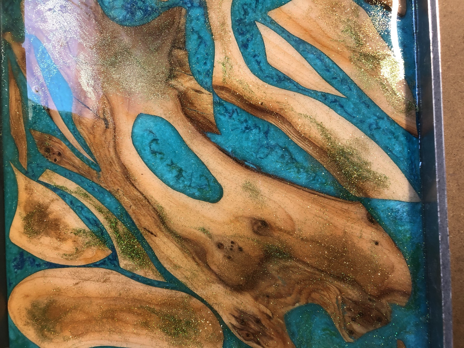 Turquoise resin poured through olive burl, workshop bench