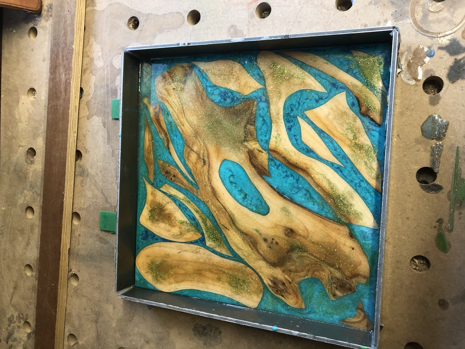 Close detail of turquoise resin and burl grain with glitter accents