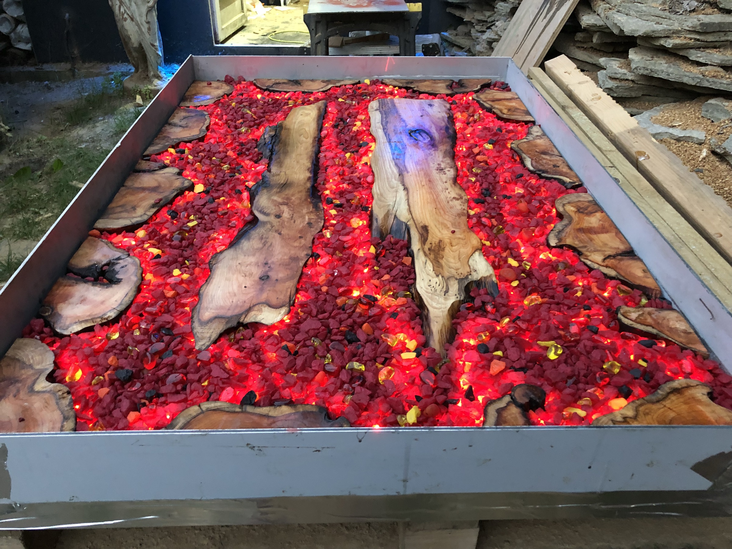 Steel-framed tray table filled with red glass and live-edge timber, LED-lit from within like embers