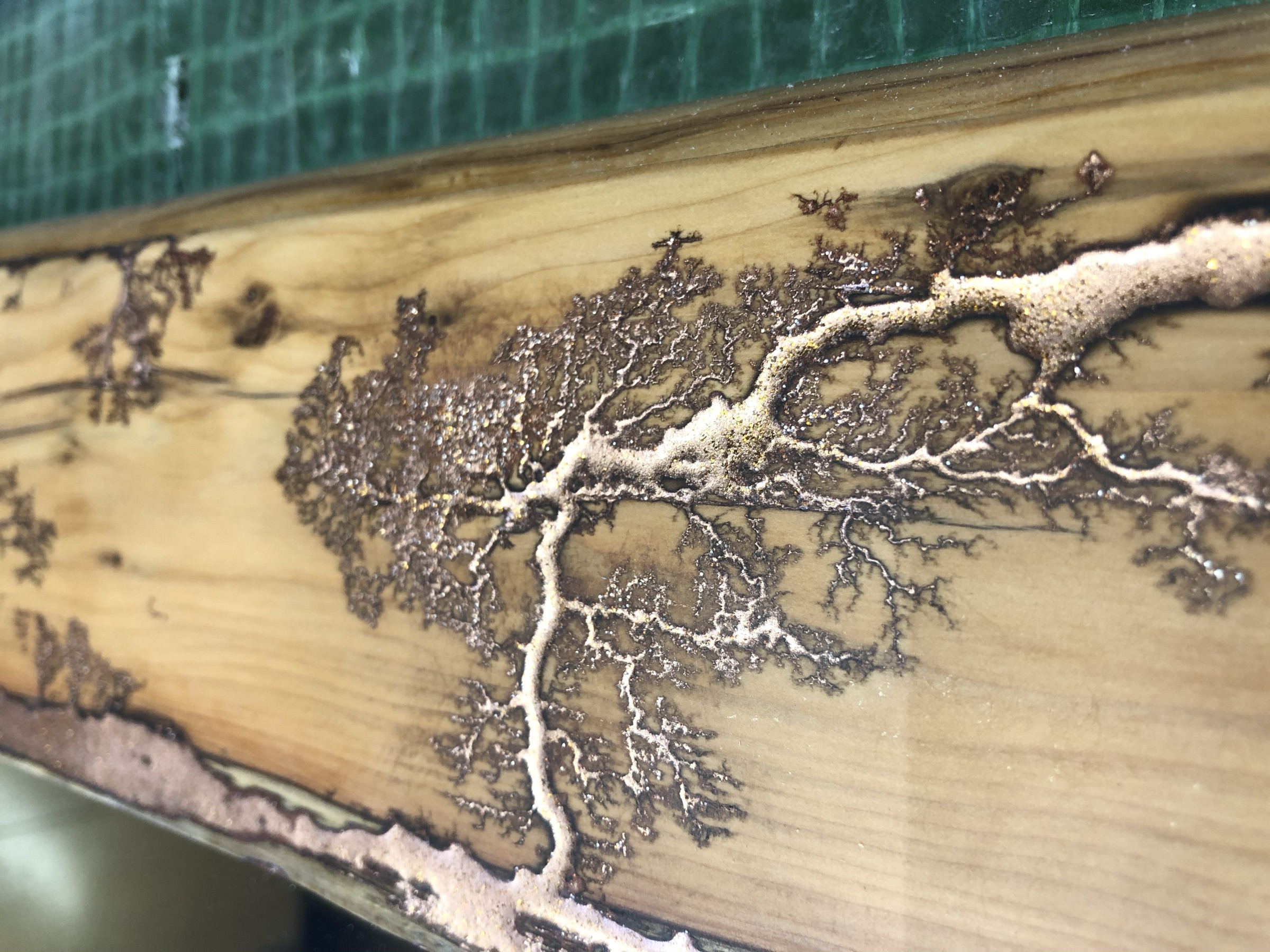 Close detail of the Lichtenberg branching burned into the frame and filled with copper, on the workbench
