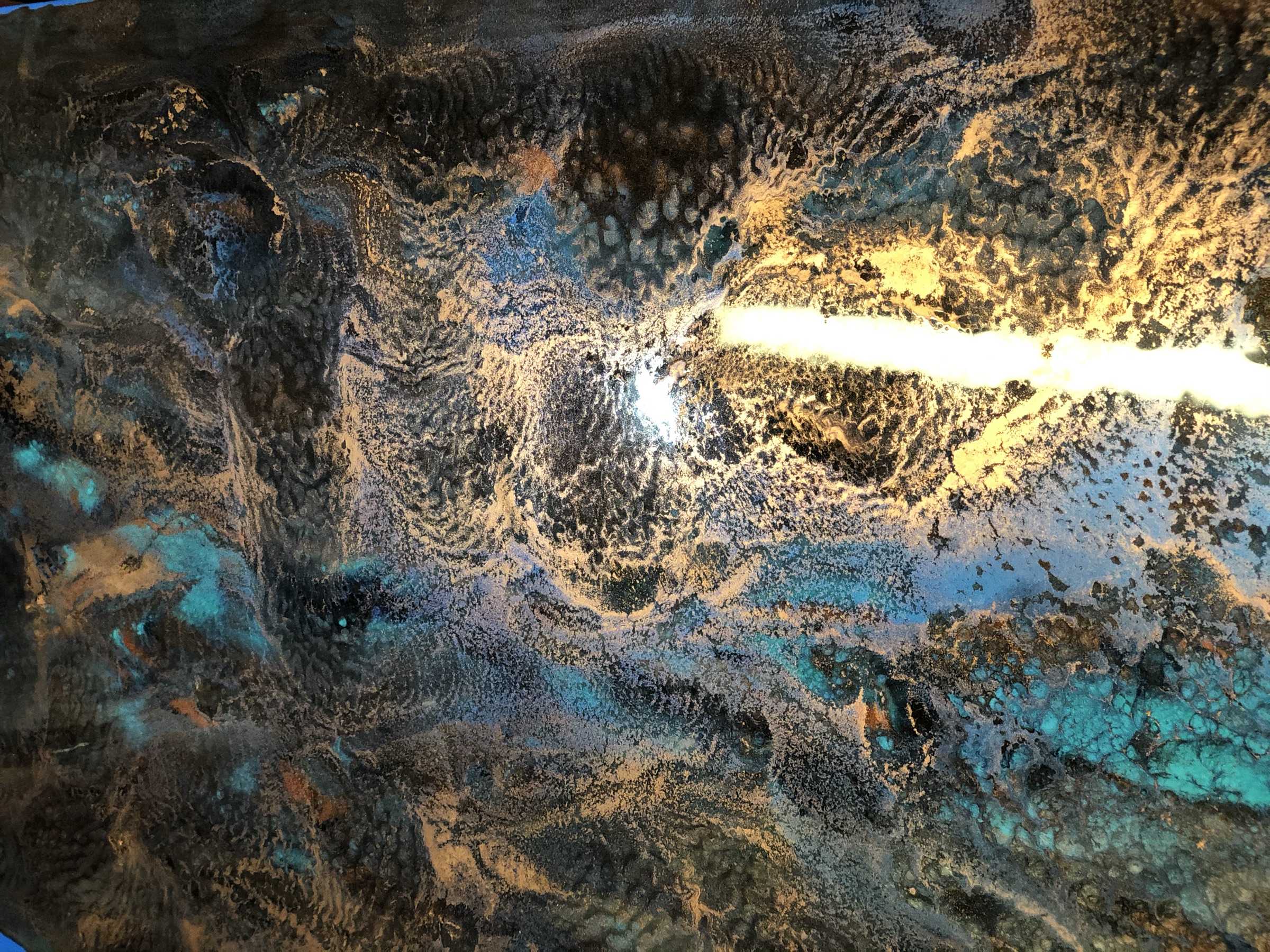 Close detail of the blue and copper marbled patina on the mirror surface