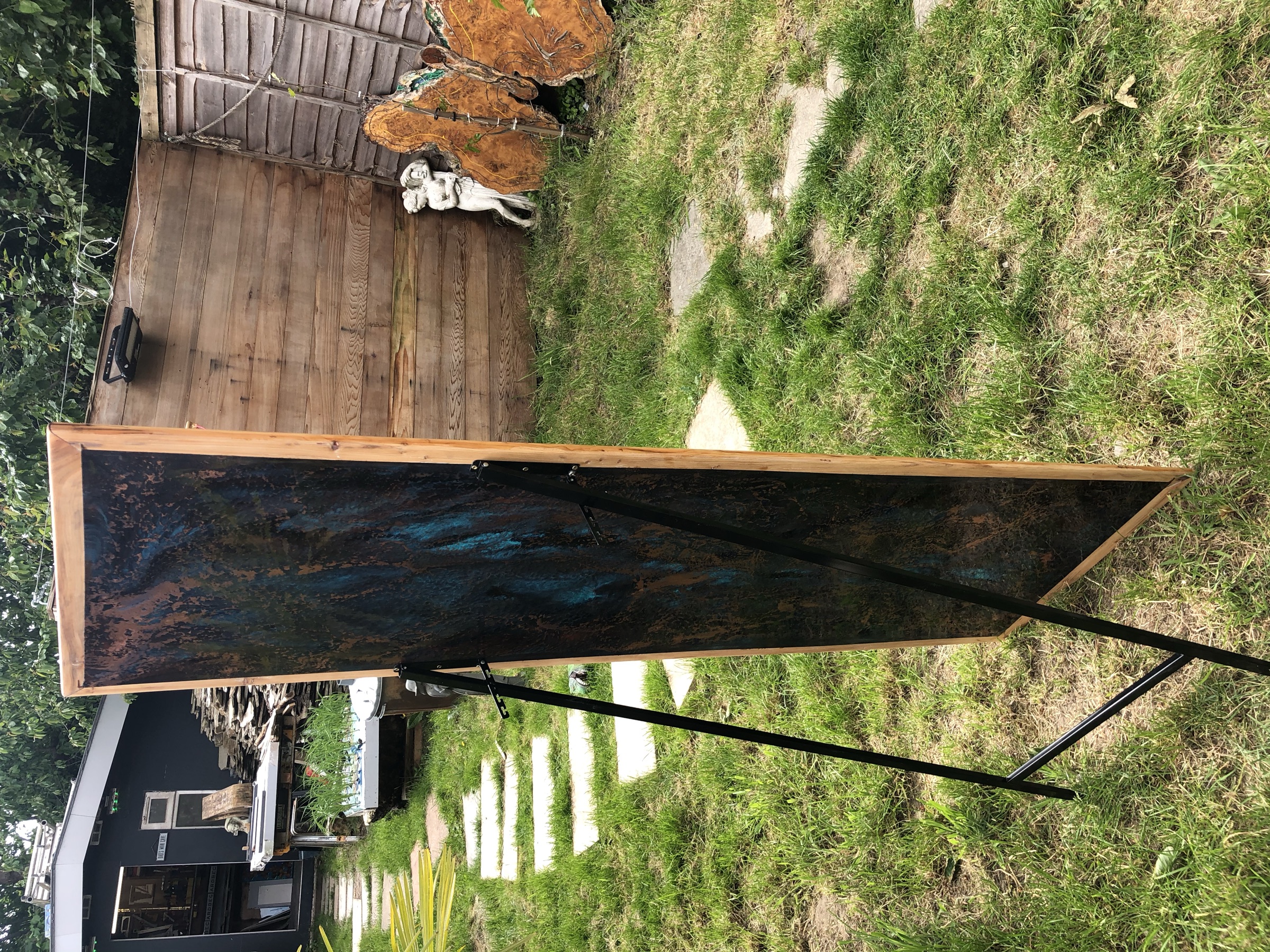 The full free-standing mirror on an easel stand outdoors, light timber frame and patinated surface