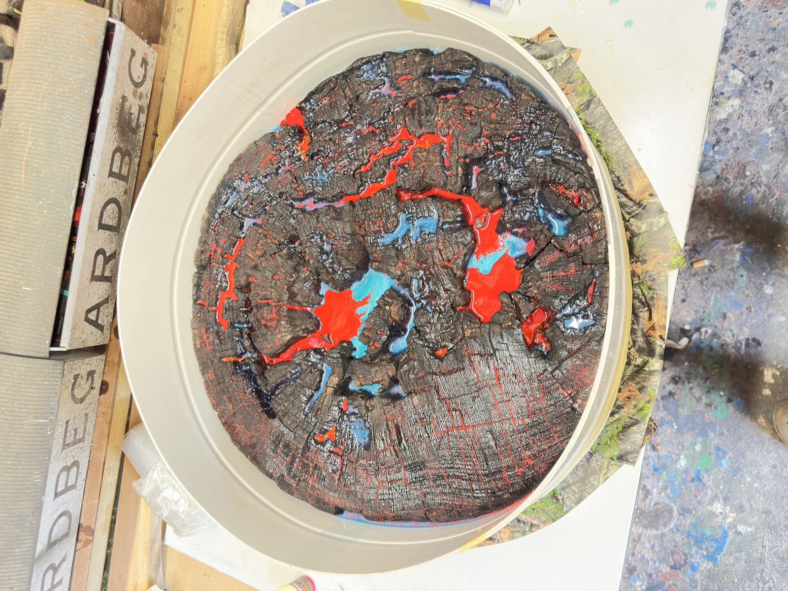 A round timber disc, deeply charred, sitting in a circular mould before resin is poured