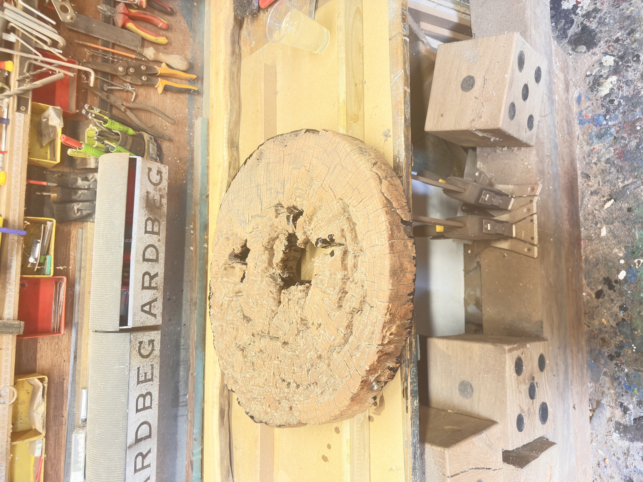 A raw, unburned timber disc on a workshop bench, before treatment