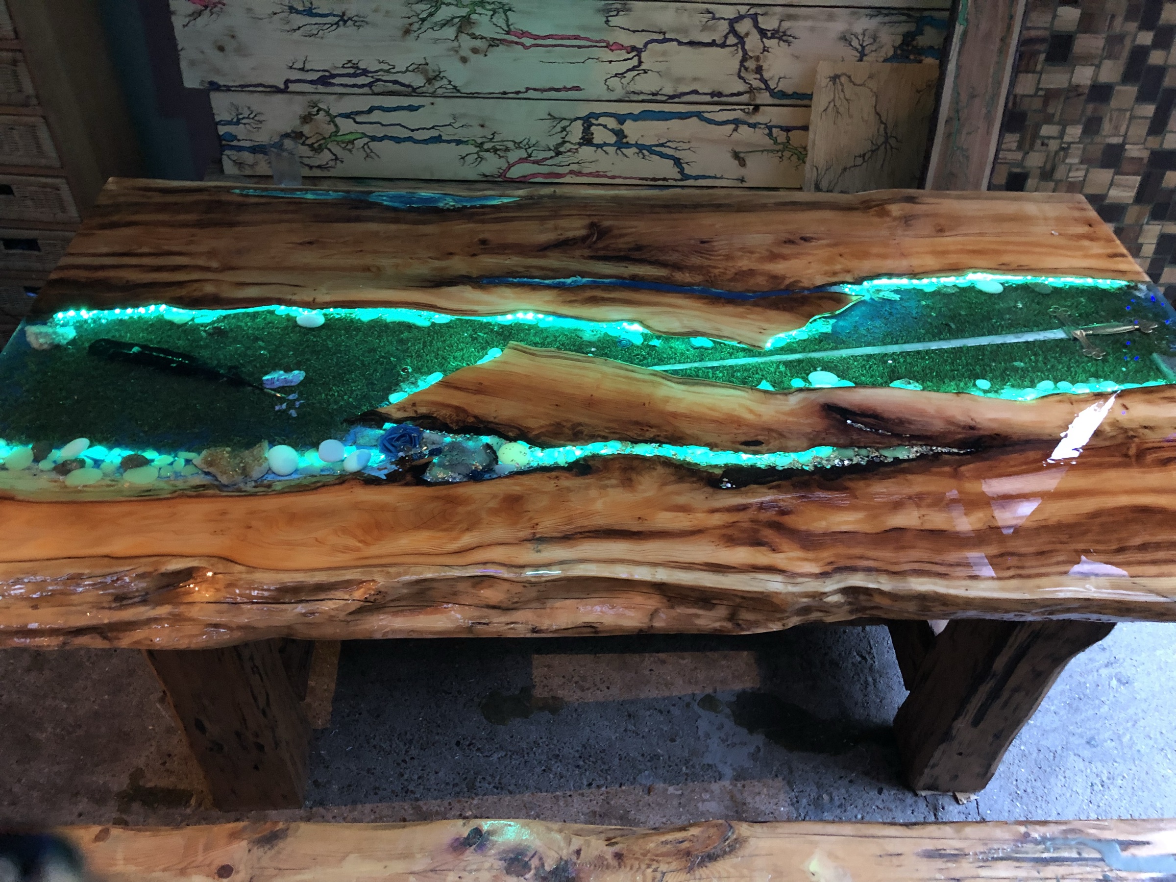The table in the workshop, glowing green under UV, alongside other pieces in progress