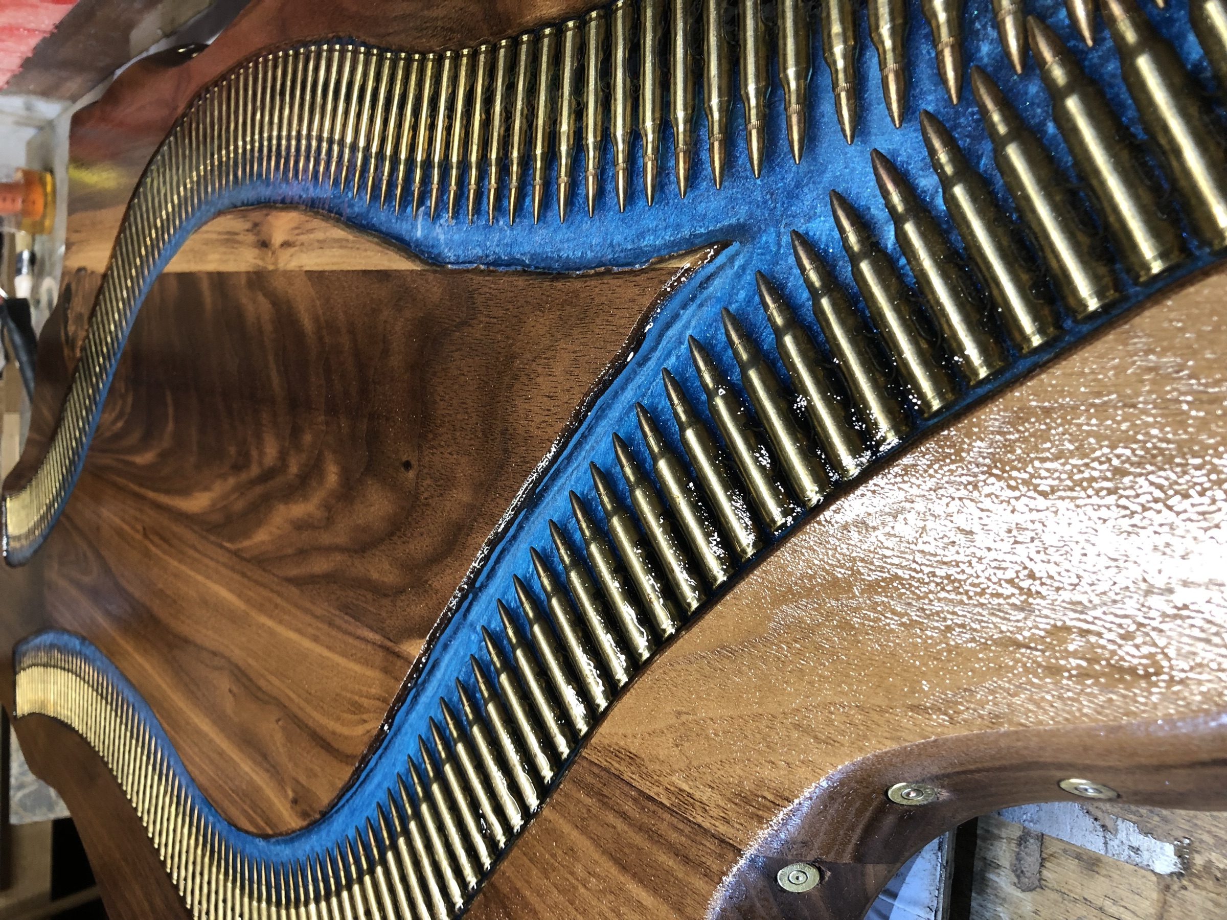 Close detail of brass cartridge casings set nose-to-tail in blue resin